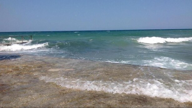 Una playa con agua cristalina y un muelle de madera.