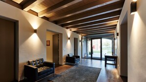 A modern interior with a wooden ceiling, a black leather sofa, and a rug. - Agriturismo La Razza (Reggio nell'Emilia)