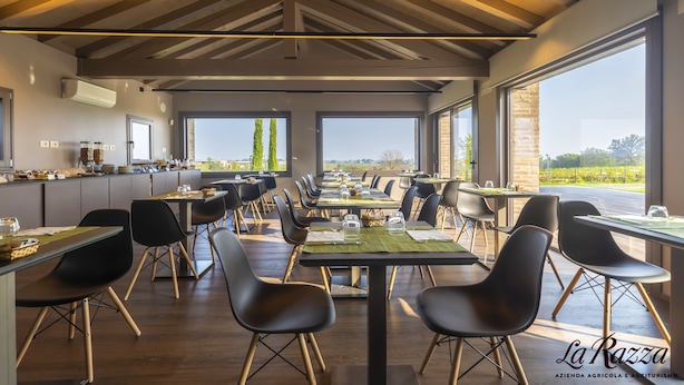 A restaurant with a long table set for dining, large windows, and a view of the outdoors. - Agriturismo La Razza (Reggio nell'Emilia)