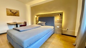 Una habitación de hotel moderna con una cama grande, un escritorio y una lámpara de pared.
