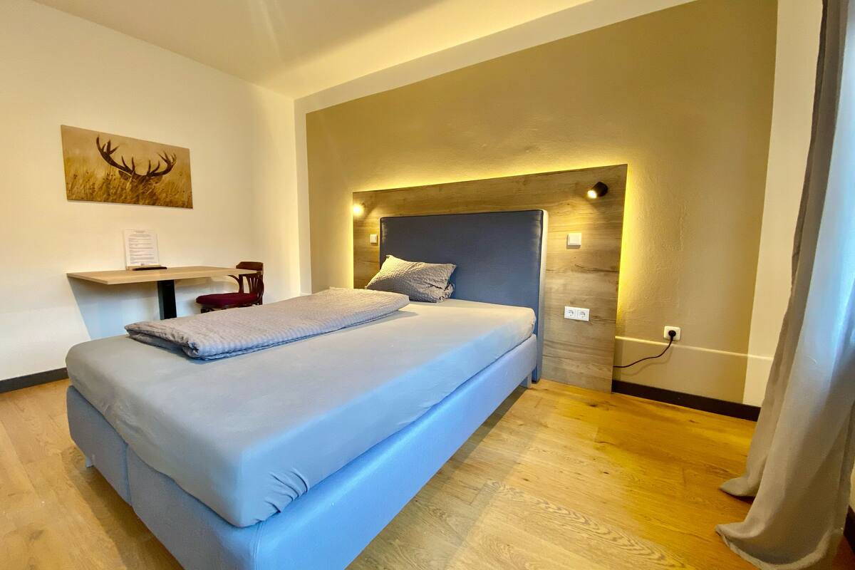 Ein modernes Hotelzimmer mit einem großen Bett, einem Schreibtisch und einer Wandleuchte.