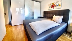 Un dormitorio moderno con una cama grande, un armario y un cuadro en la pared.