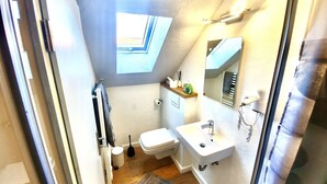 Un baño pequeño con tragaluz, inodoro, lavabo y espejo.