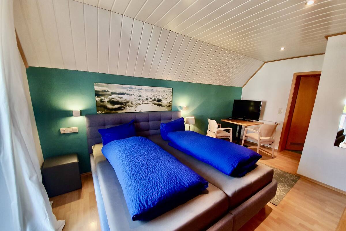 Ein modernes Hotelzimmer mit einem großen Bett, einem Schreibtisch und einem Fernseher.