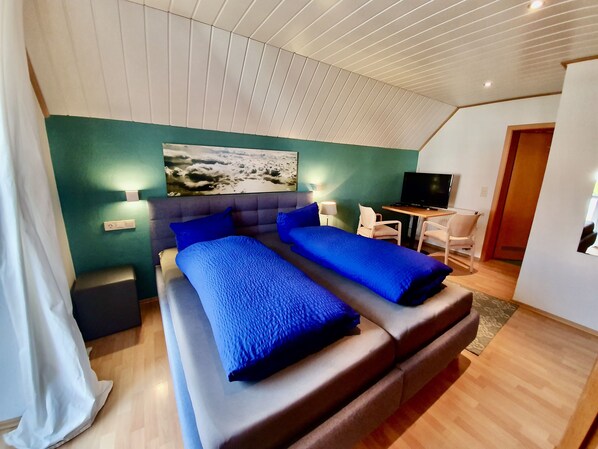 A modern hotel room with a large bed, a desk, and a television. - Almehof Thöne (Bueren)