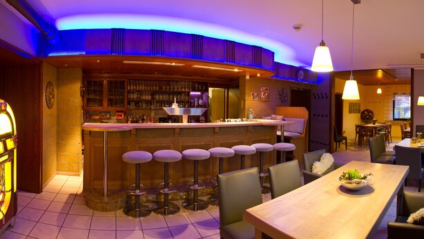 Zona de bar con taburetes, una barra y una máquina recreativa.
