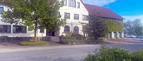 A two-story building with a red roof, a sign that reads 'Hotel Spitzer Wirt,' and a paved driveway leading to the entrance.