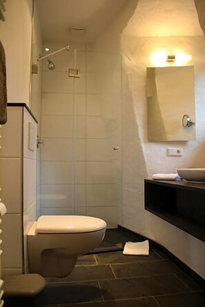 A modern bathroom with a toilet, shower, and sink.
