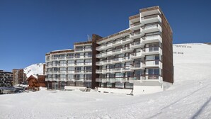 Een meerlaags hotel met balkons, gelegen in een besneewd gebied met een skipiste in de buurt.