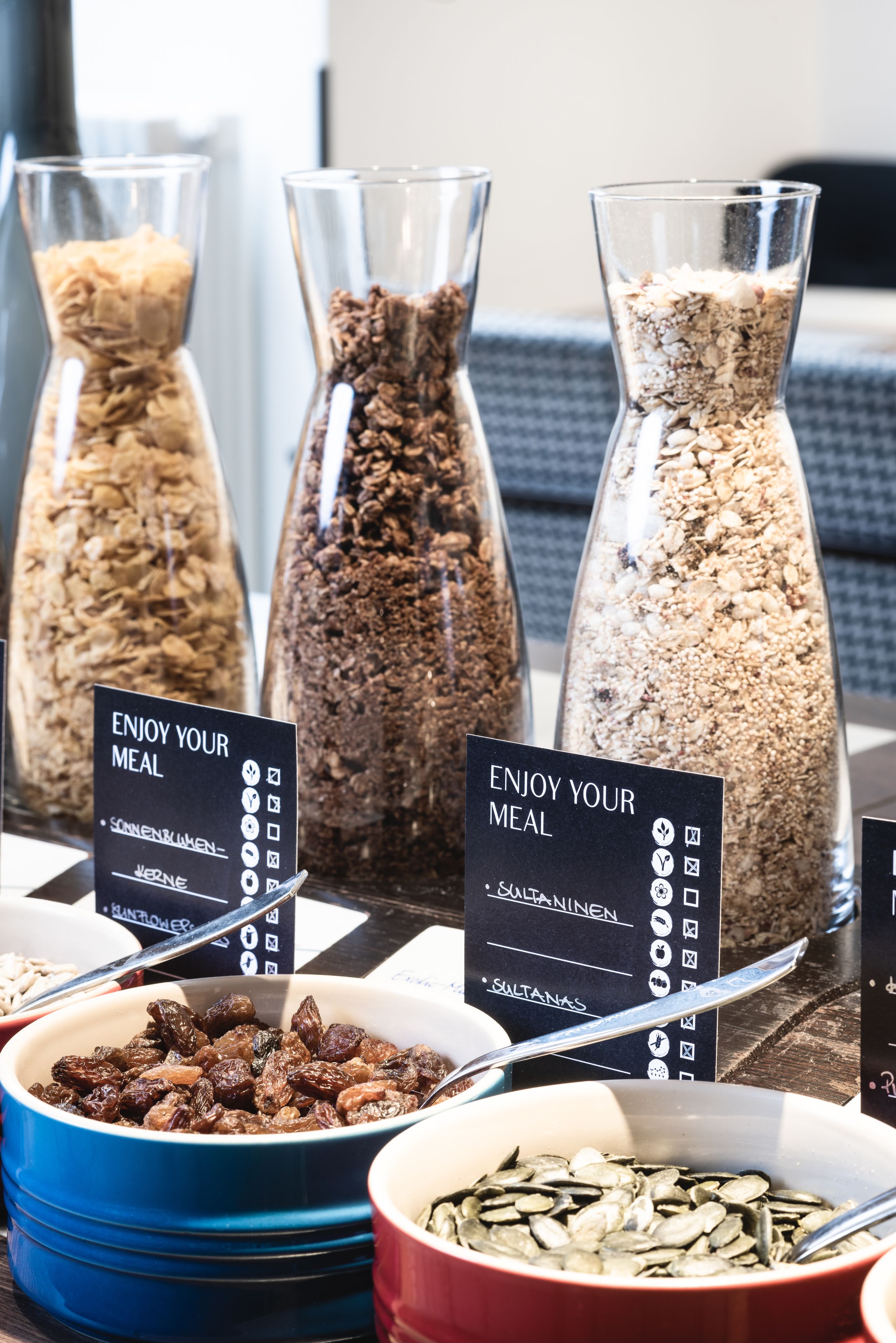 A buffet with various food options in clear containers, each labeled with a sign indicating the type of food.