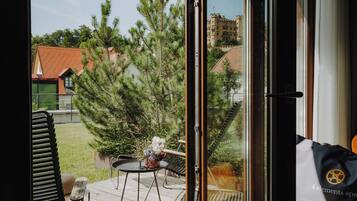 Vista da una stanza con porta scorrevole su un terrazzo esterno. Il terrazzo presenta un tavolo con sedie e un'amaca.