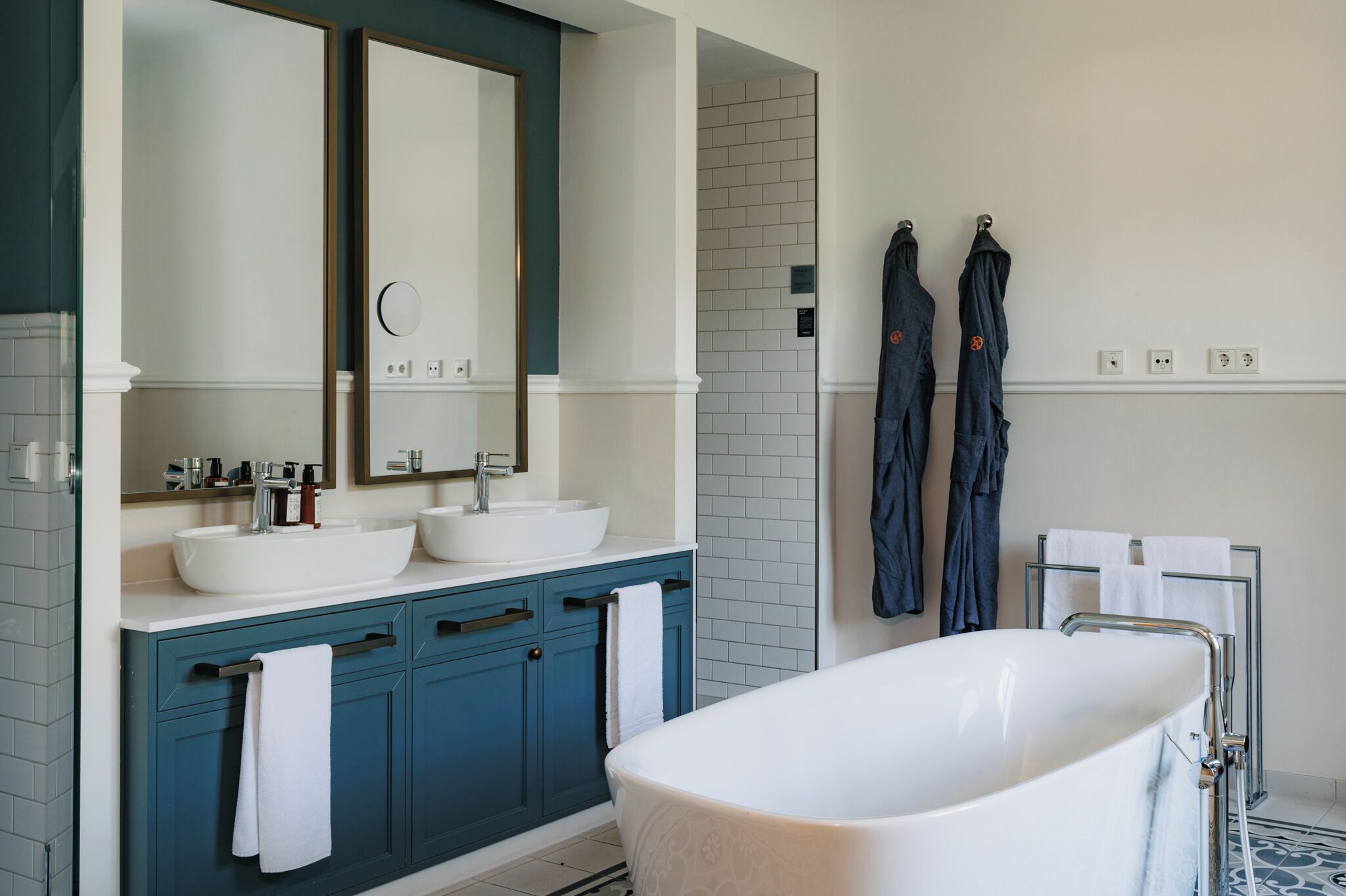 Ein modernes Badezimmer mit zwei Waschbecken, einem großen Spiegel und einer freistehenden Badewanne.