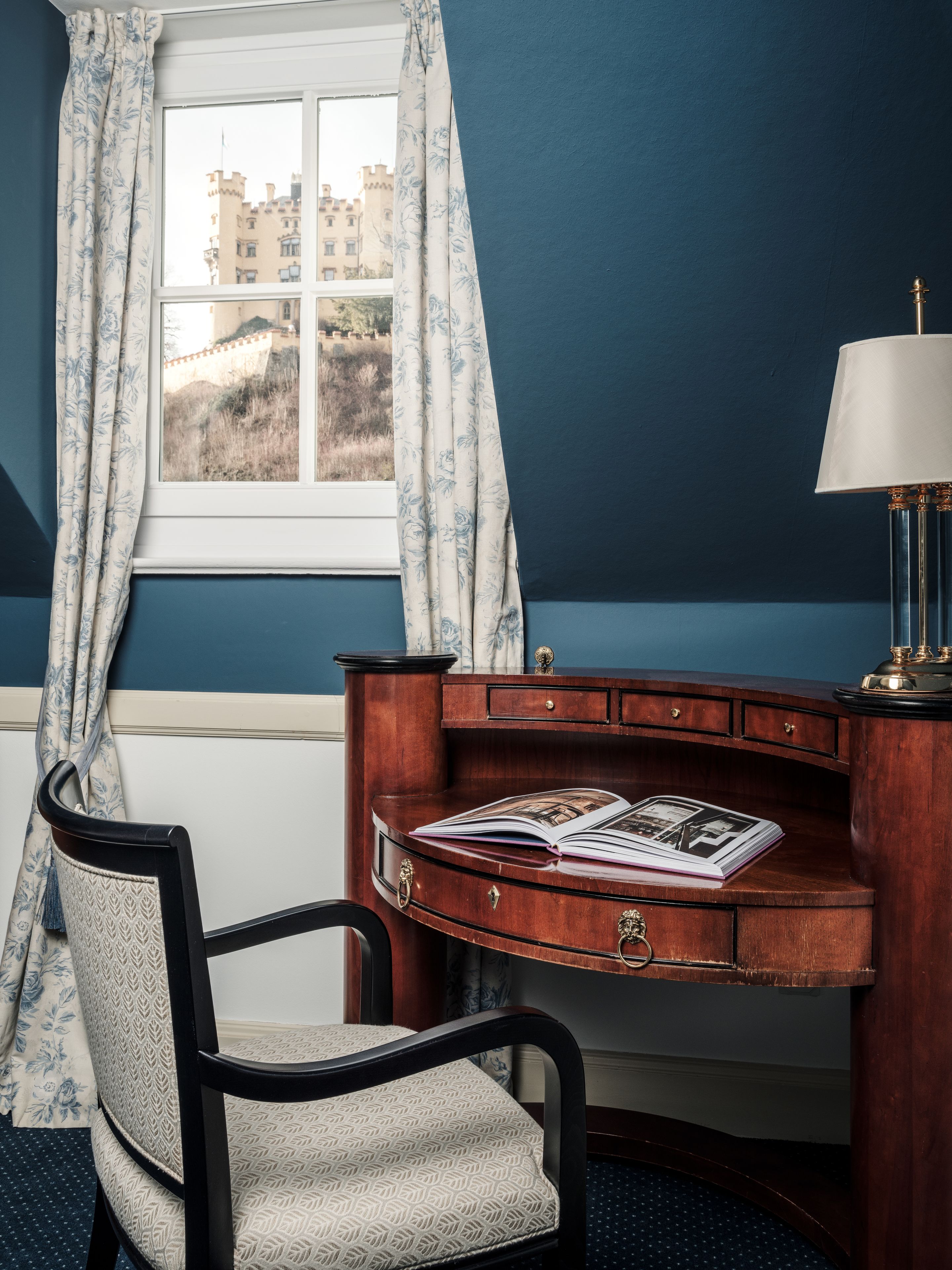 Une pièce comprenant un bureau, une chaise et une fenêtre avec des rideaux.