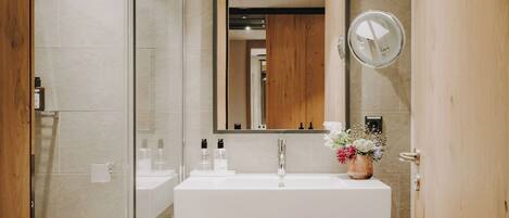A modern bathroom with a white sink, mirror, and wooden accents.