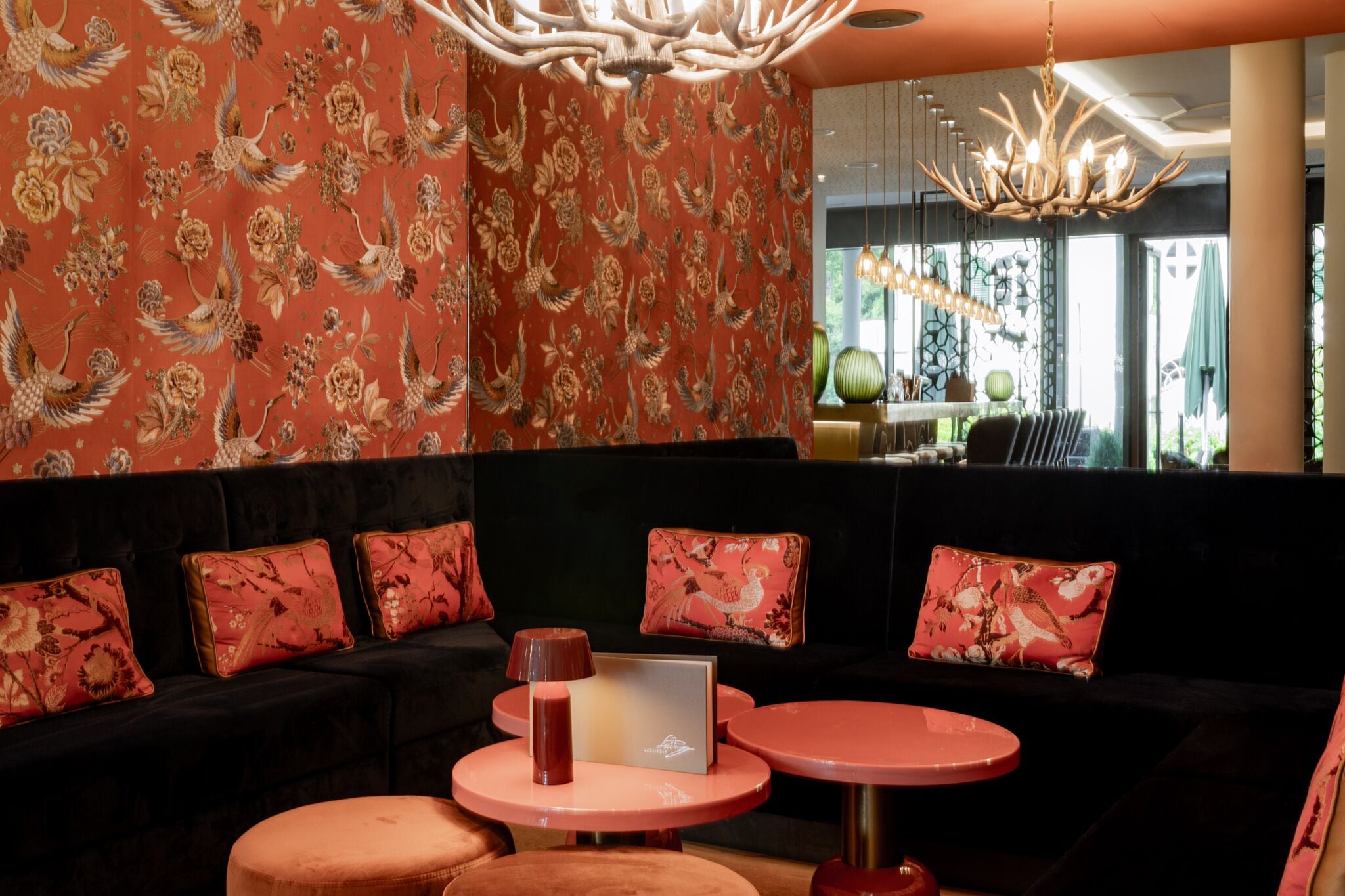 A modern lounge area with a dark sofa adorned with floral cushions, a laptop on a small table, and a unique chandelier.