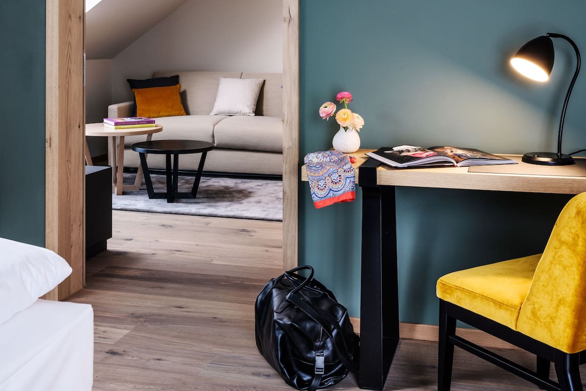 A modern room with a desk, a yellow chair, a black bag, and a sofa with a white cushion.