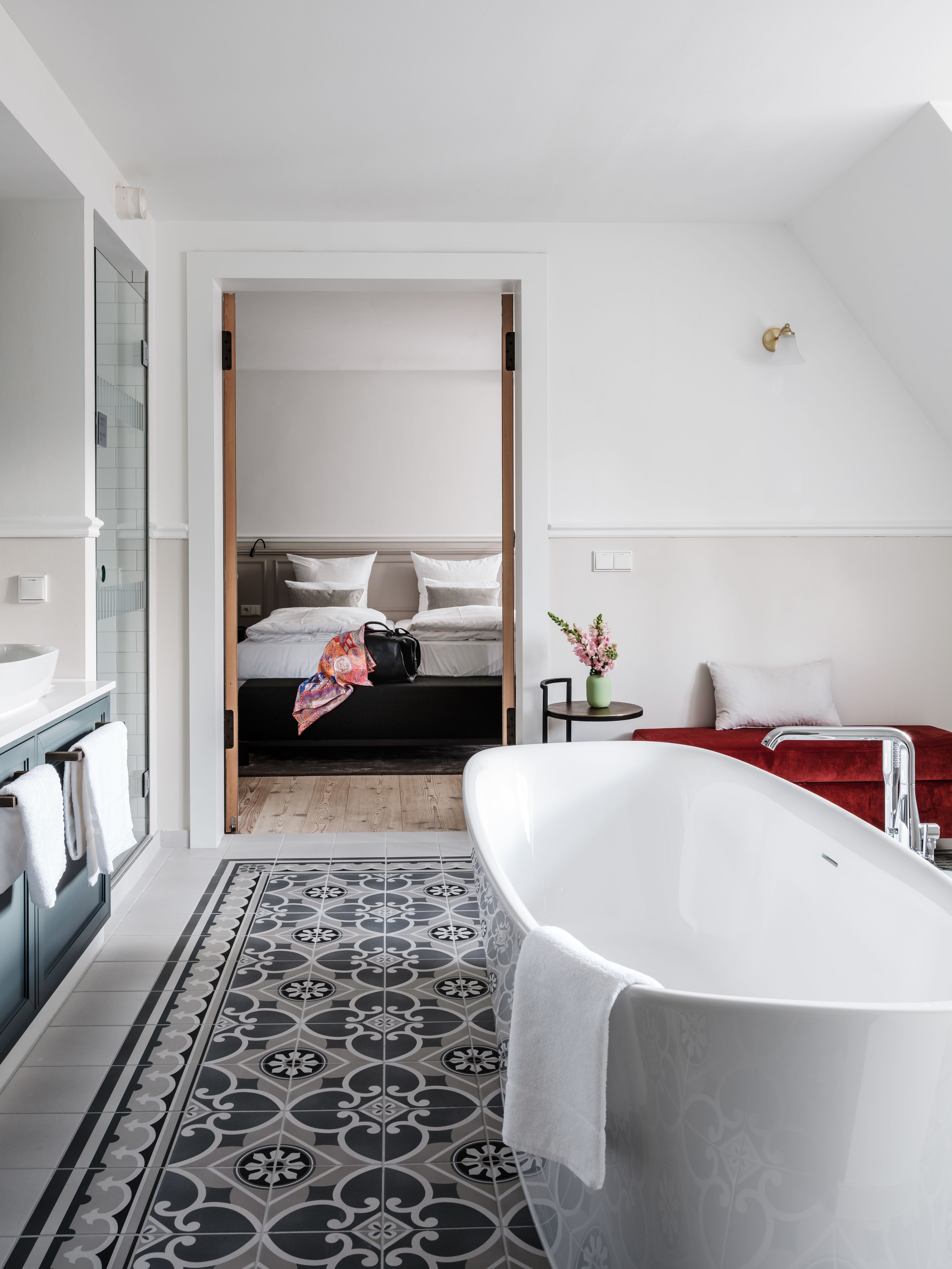 Ein modernes Badezimmer mit freistehender Badewanne, einem großen Spiegel und einem gemusterten Boden.