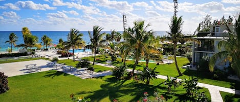 A resort with a pool, palm trees, and a view of the ocean.