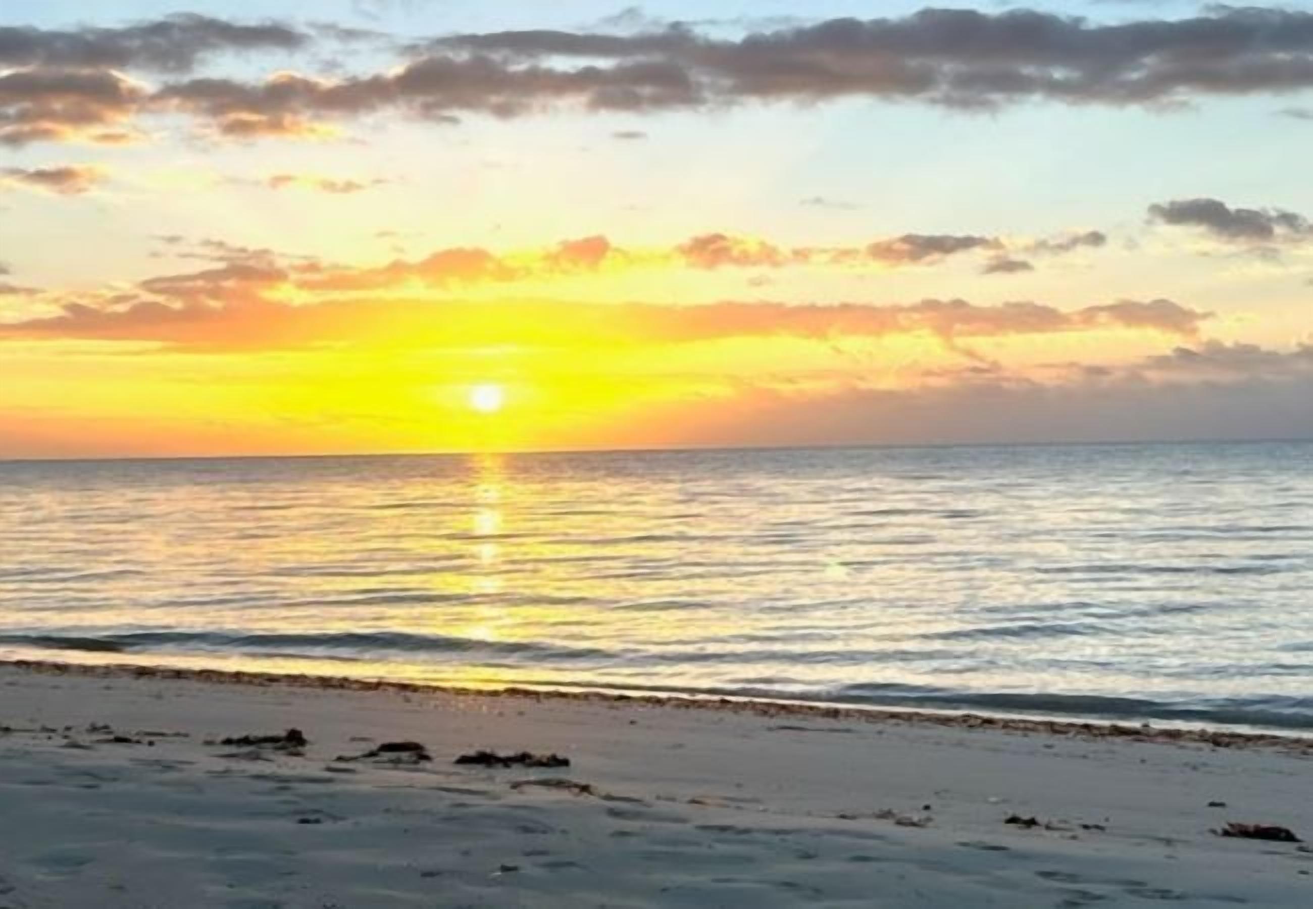 A beach with a sunset over the ocean.
