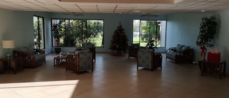 A spacious living room with a high ceiling, large windows, and a Christmas tree.