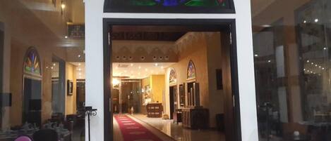 A hotel lobby with a red carpet, a reception desk, and a glass entrance.