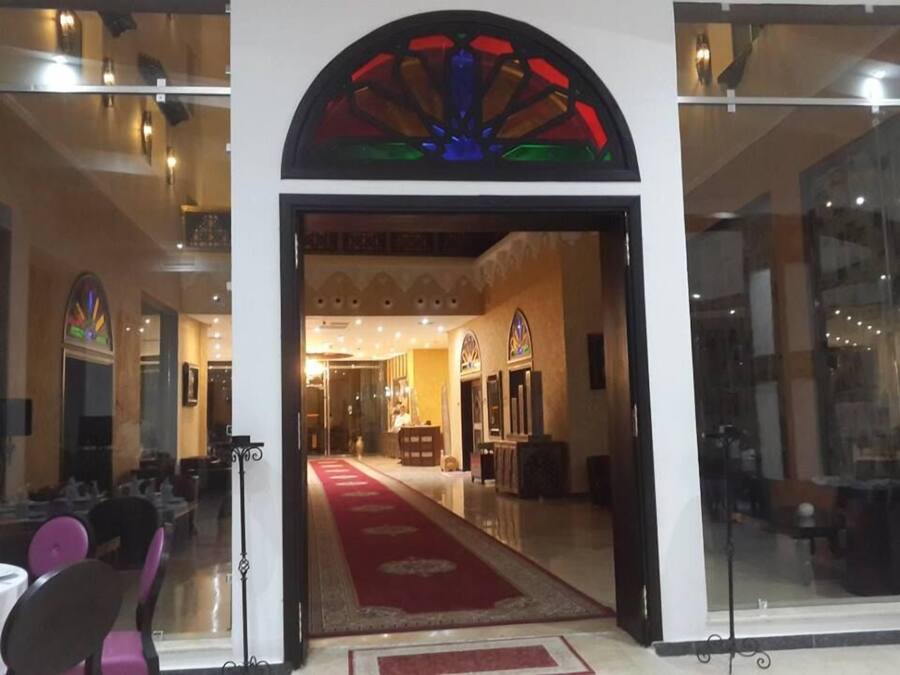 Un'hall dell'hotel con tappeto rosso, reception e ingresso in vetro.