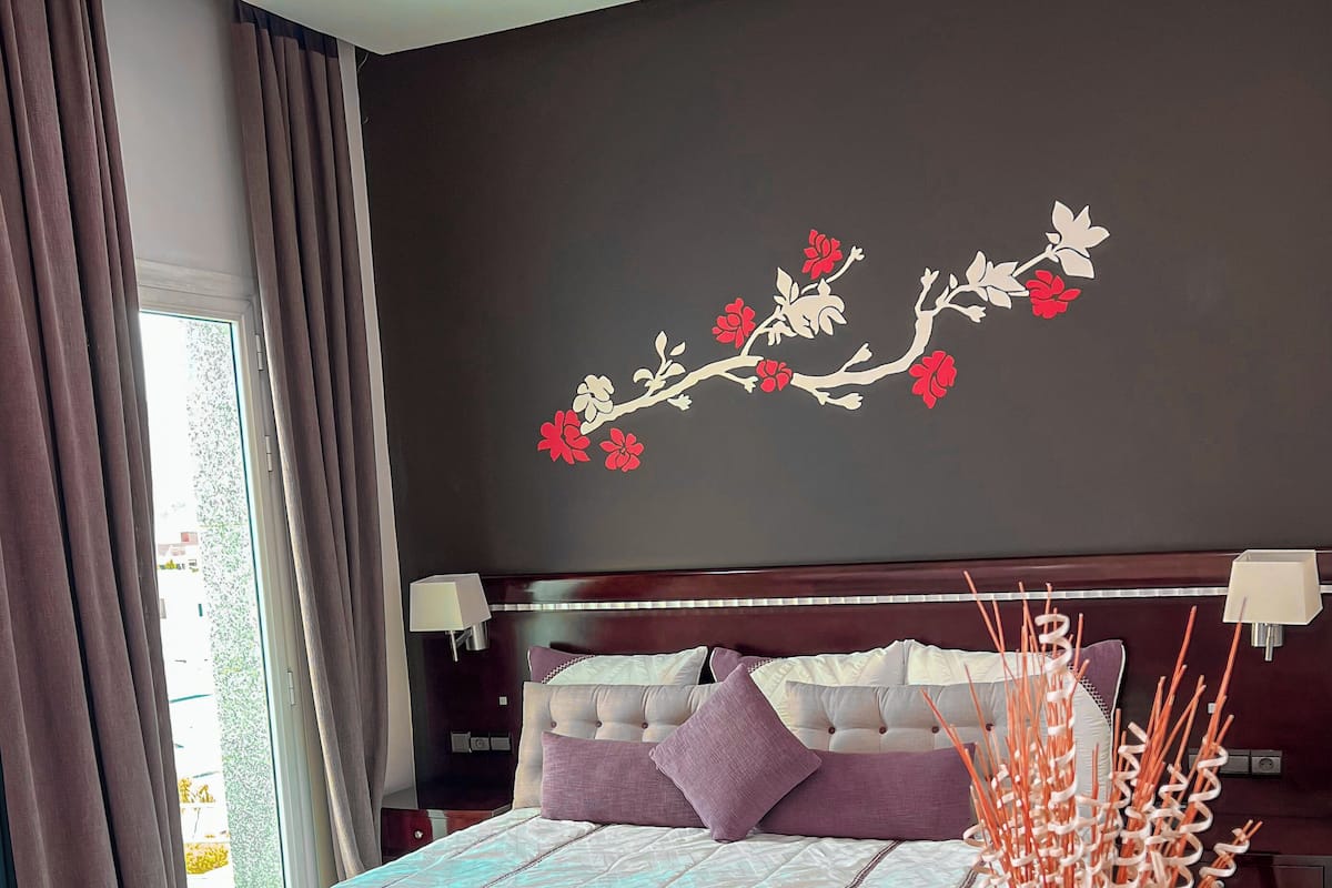 Ein Schlafzimmer mit einem großen Bett, dunklen Wänden und einer Blumenbordwand.