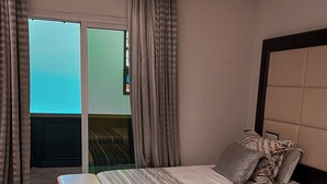 Hotellihuone, jossa on sänky, penkki ja ikkunasta avautuva näkymä taivaalle.