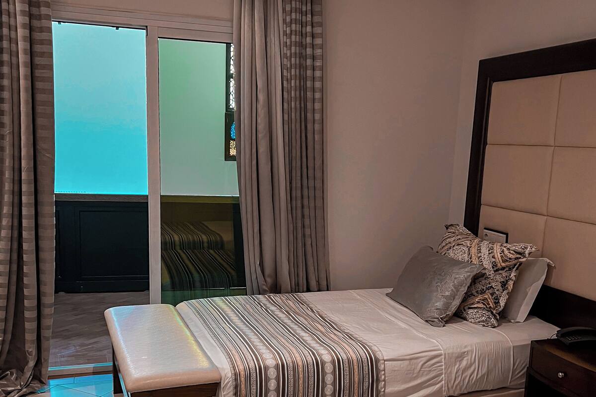 Ein Hotelzimmer mit einem Bett, einer Bank und Blick zum Himmel durch ein Fenster.