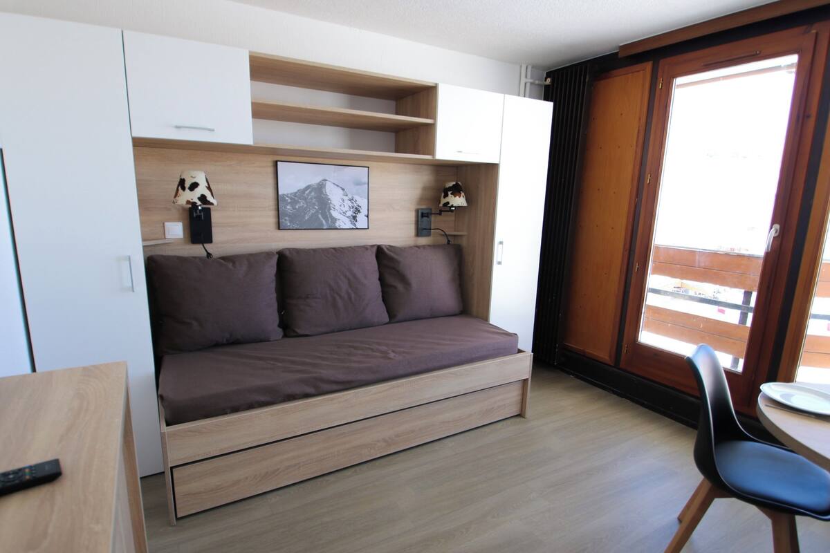 Ein kleines Zimmer mit Schlafsofa, Schreibtisch, Stuhl und Fenster mit Blick.
