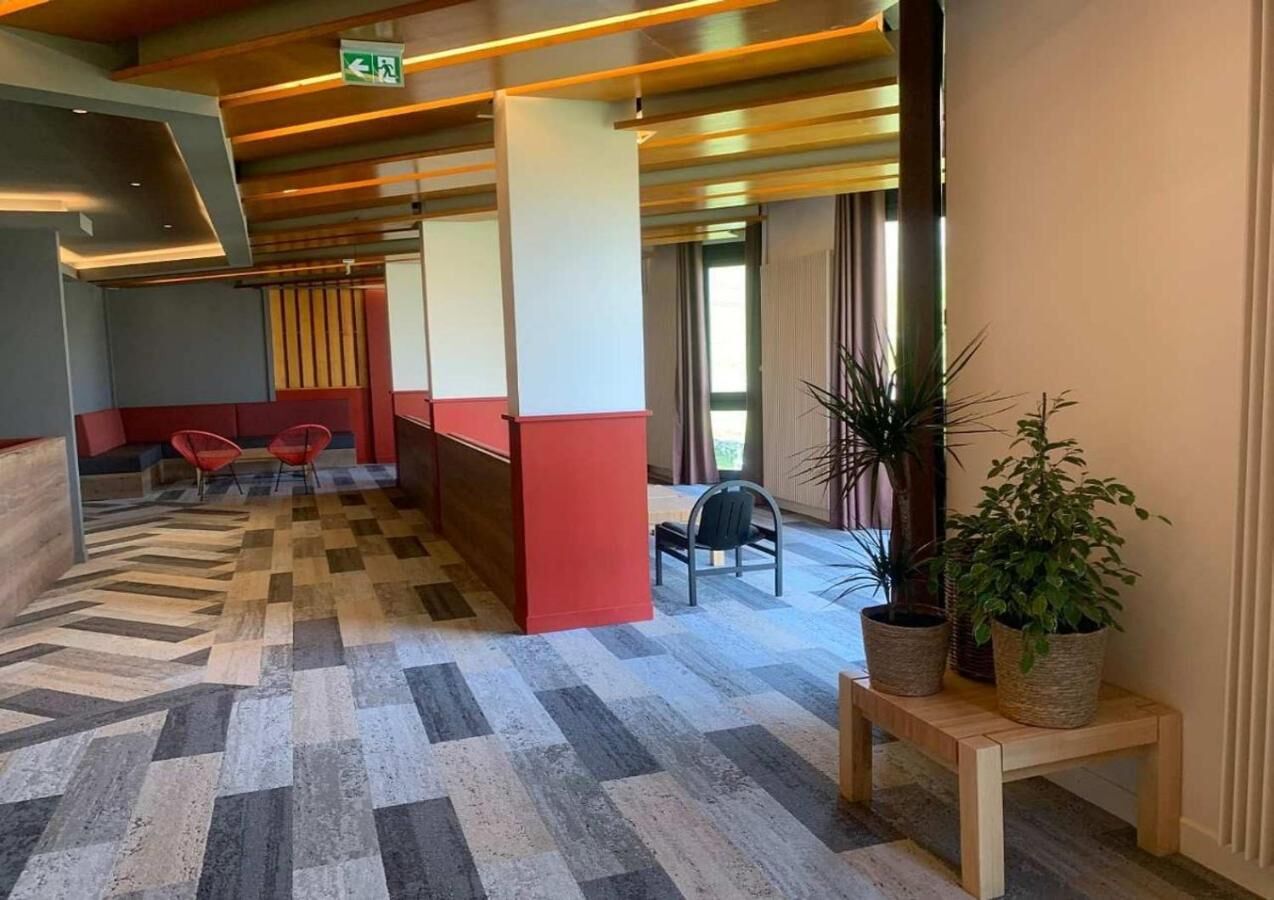 A hotel lobby with a checkered floor, red and white walls, and a wooden reception desk.