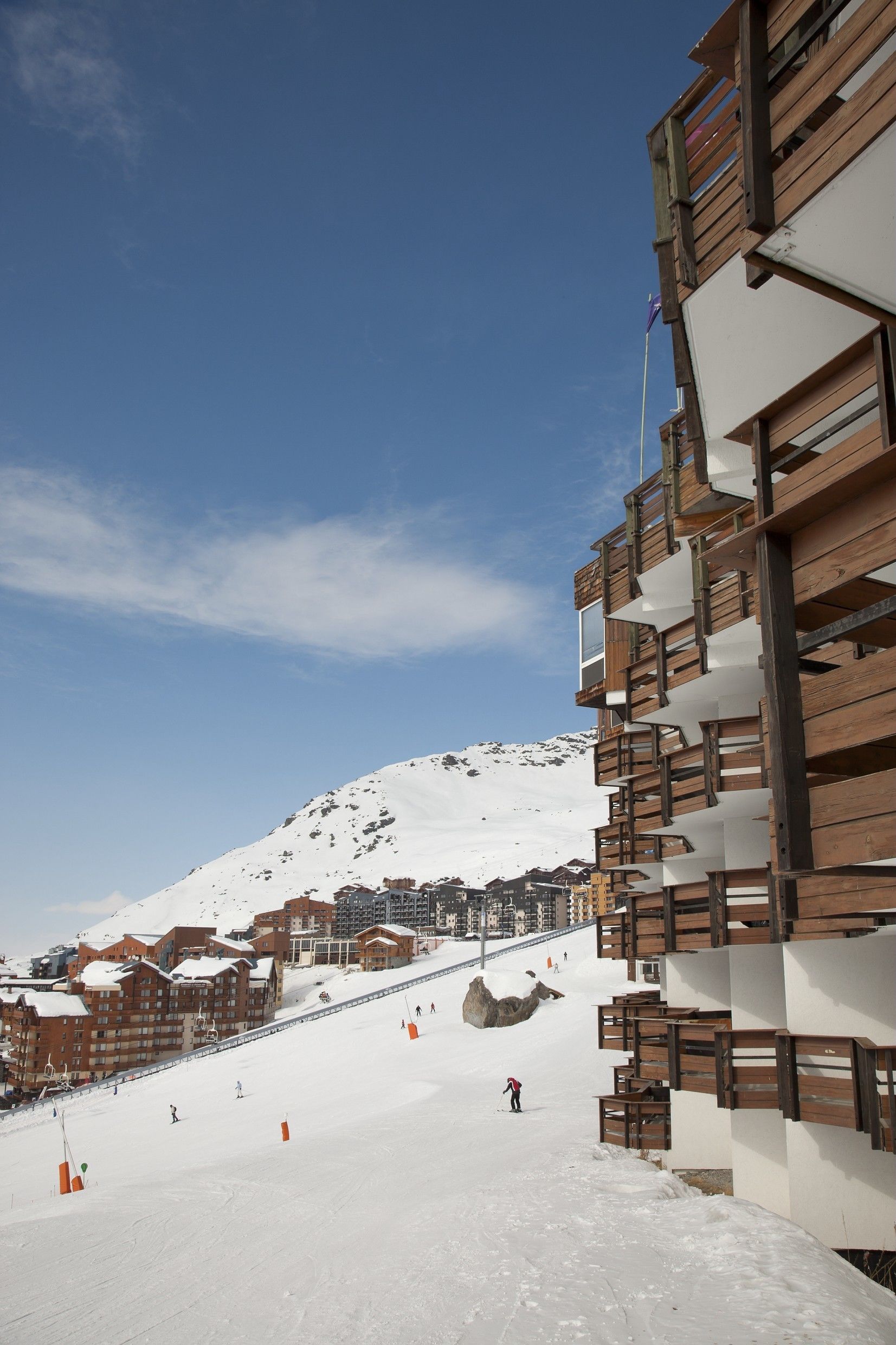 A snow-covered ski slope with wooden buildings and a clear sky.