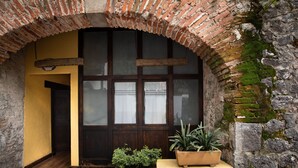 Un arco de entrada con una puerta de madera, una planta en maceta y un muro de piedra.
