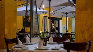 Un restaurante con una mesa dispuesta para dos personas, con mantel blanco, platos y servilletas.