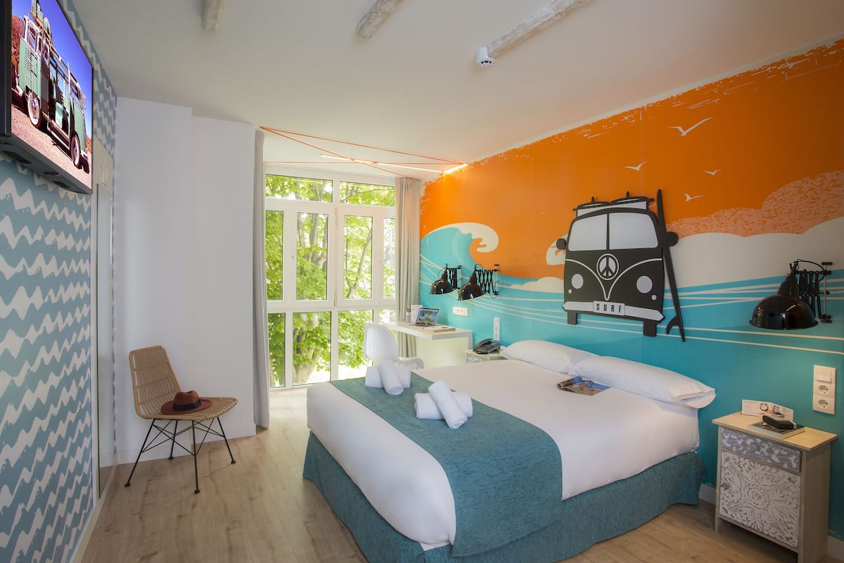 Une chambre à coucher avec un lit, une chaise, un bureau et un téléviseur fixé au mur.