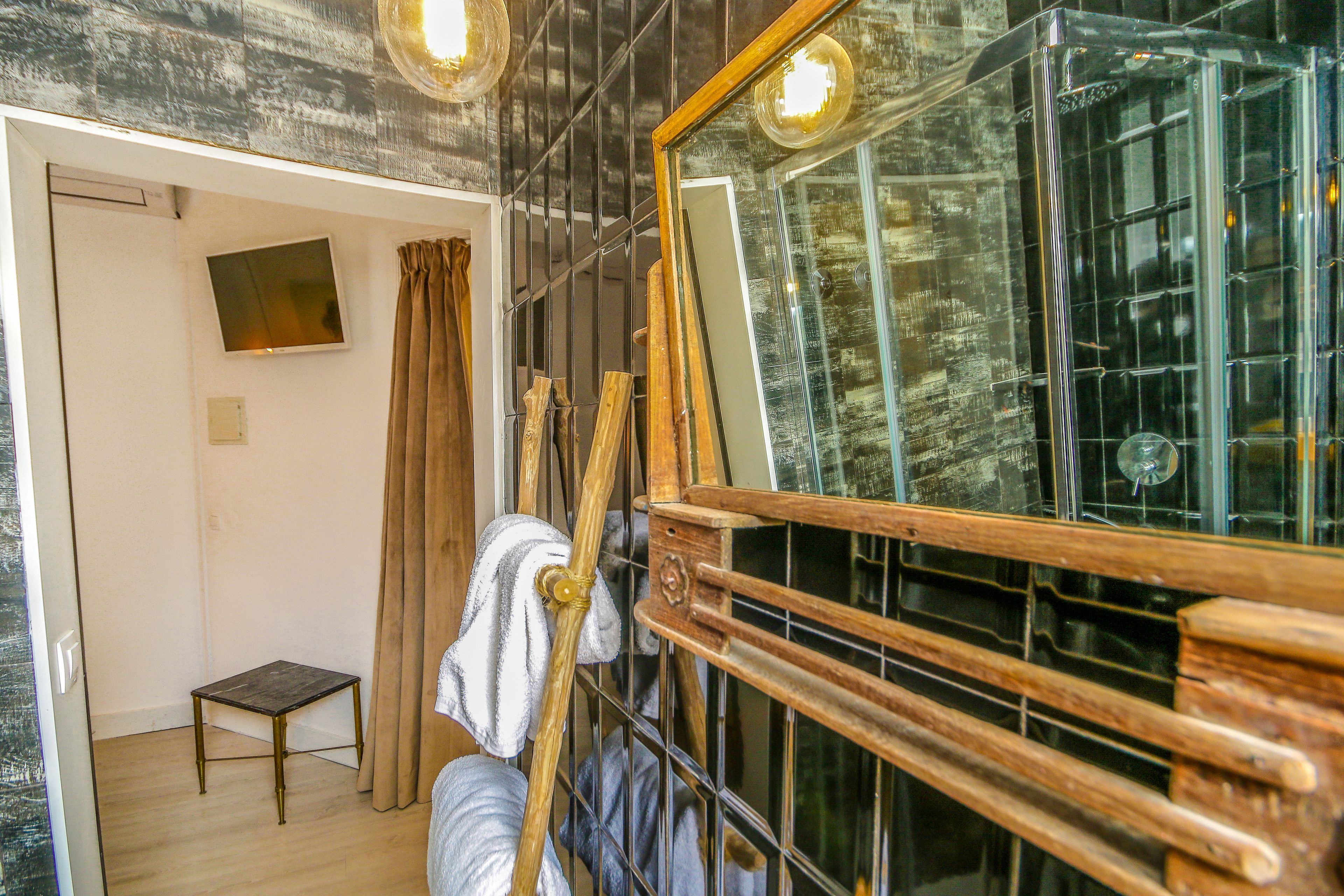 Una habitación con un cabecero de madera, una mesita pequeña y un espejo grande.