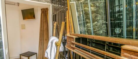 Una habitación con un cabecero de madera, una mesita pequeña y un espejo grande.