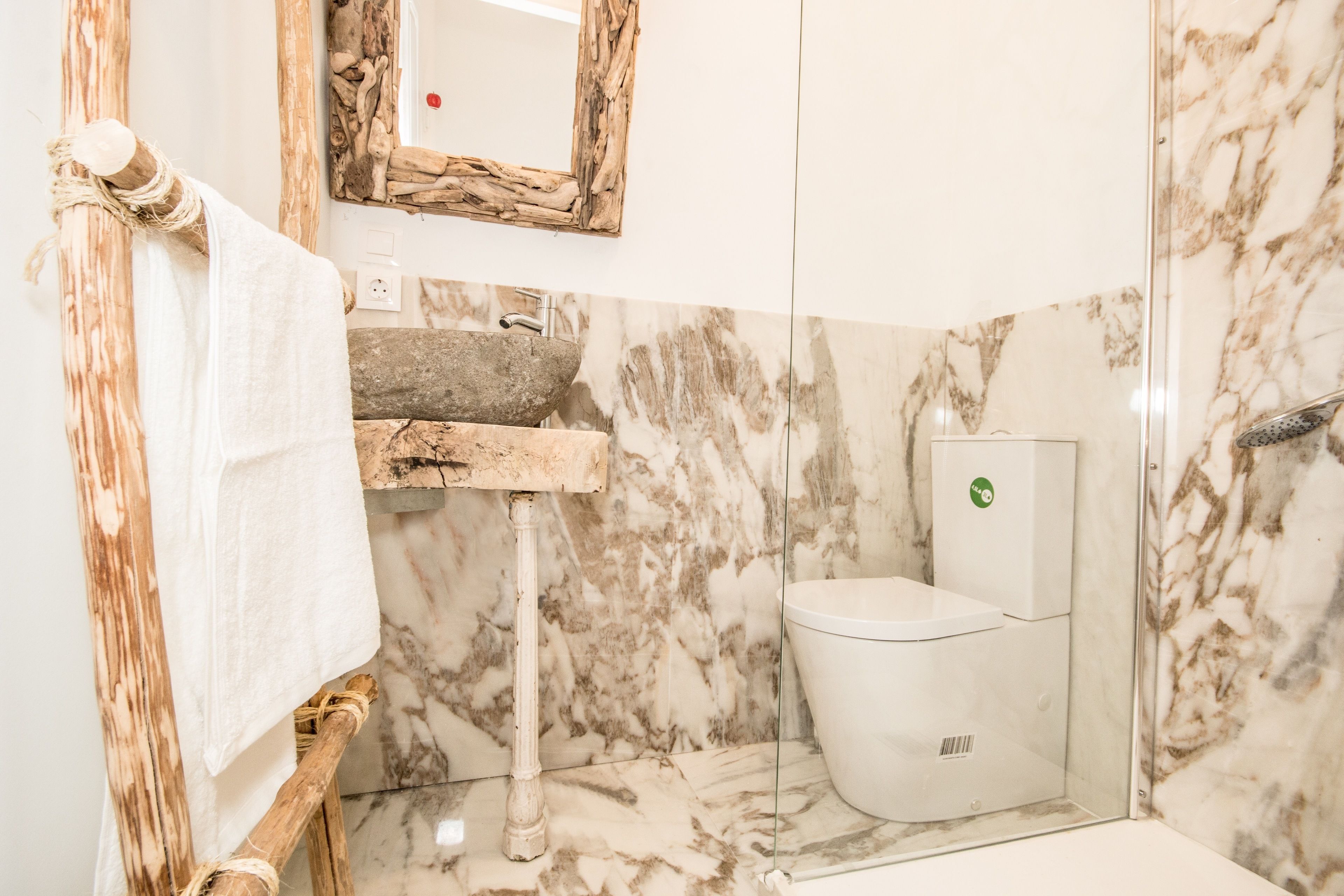 Ein Badezimmer mit Marmorwaschbecken, Toilette und einem hölzernen Handtuchhalter.