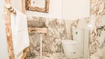 Ein Badezimmer mit Marmorwaschbecken, Toilette und einem hölzernen Handtuchhalter.
