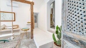 A modern interior with a swing chair, a wooden beam, a cactus plant, and a rustic wall panel. - Garam Lisboa (Lisbon)