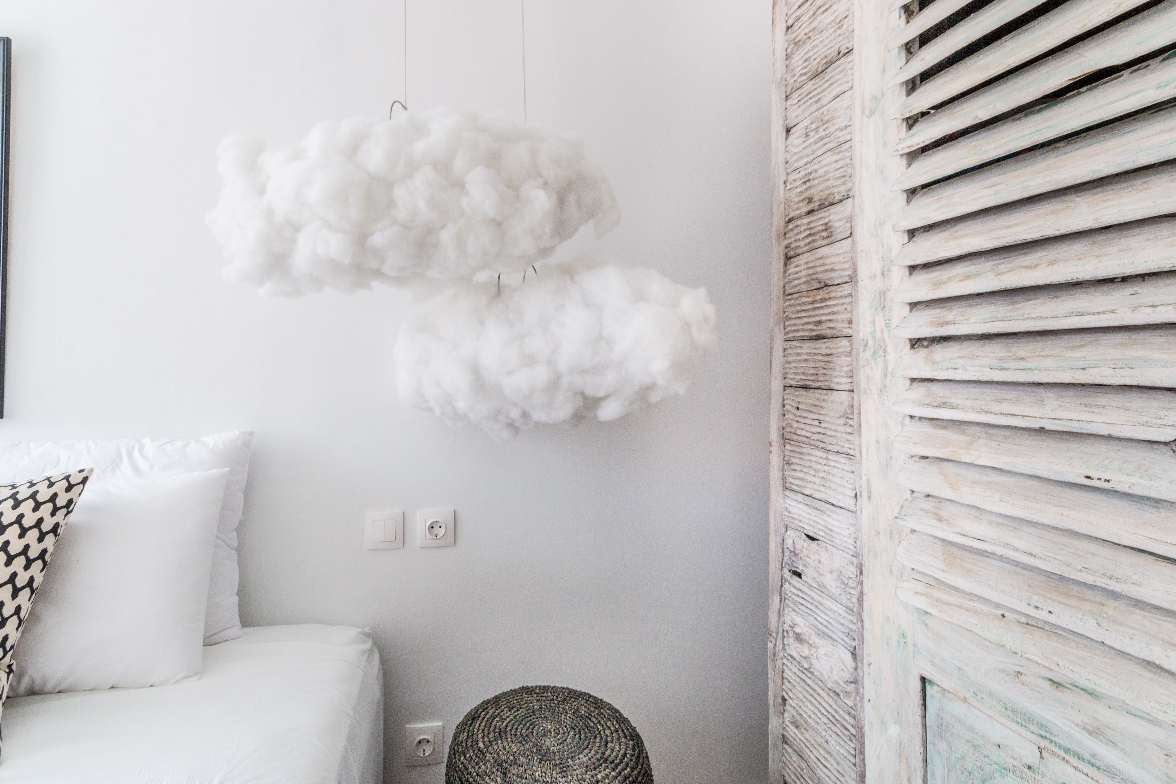Una habitación blanca con una cama, un adorno mullido en la pared y un panel de pared de listones de madera.