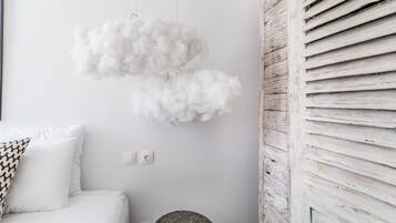 Una habitación blanca con una cama, un adorno mullido en la pared y un panel de pared de listones de madera.