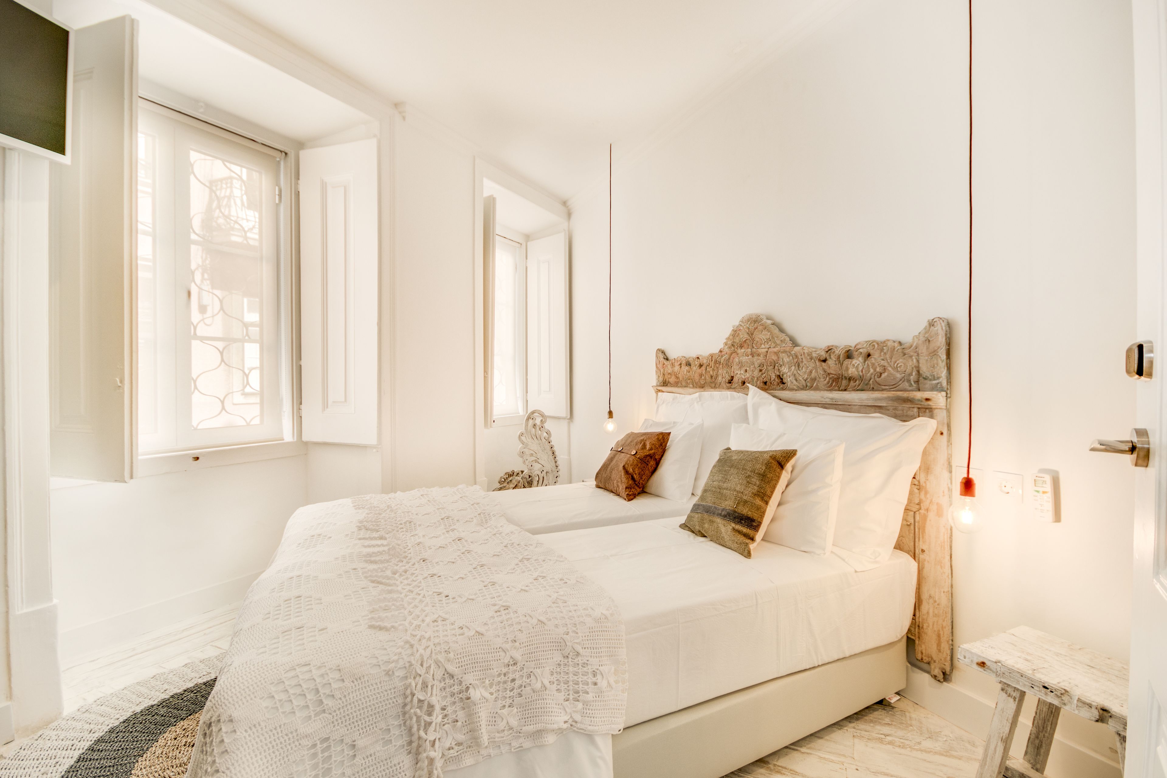 A bedroom with a large bed, two bedside tables, a wooden headboard, and a window with a view.