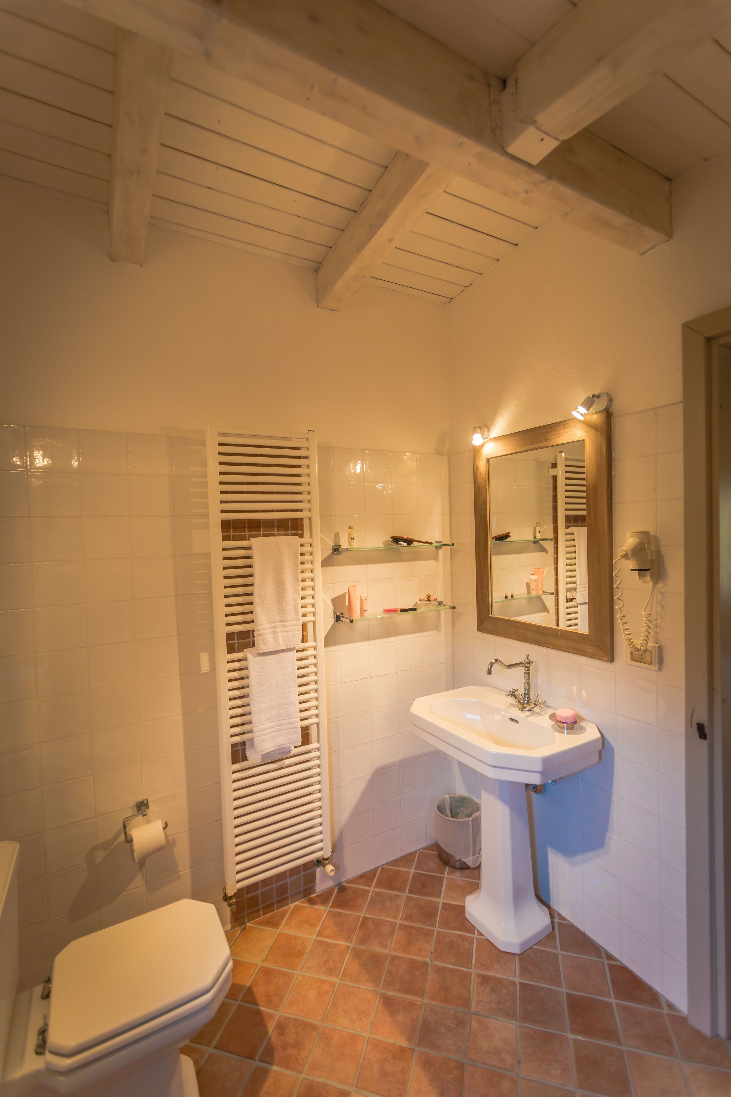 Une salle de bain comprenant des toilettes, un lavabo, un miroir et un porte-serviettes.