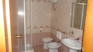 A bathroom with a shower, two toilets, and two sinks.