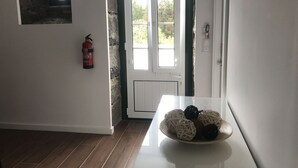 Ein Zimmer mit einer weißen Tür, einem an der Wand montierten Feuerlöscher und einer Tischplatte mit Dekorationen.