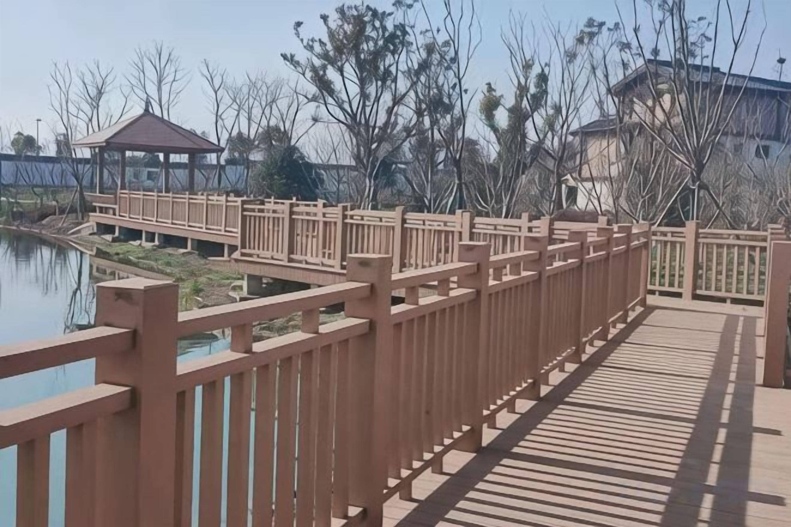 Un puente de madera con barandillas que conduce a un edificio con estructura cubierta.