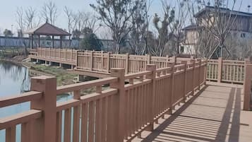 Un puente de madera con barandillas que conduce a un edificio con estructura cubierta.