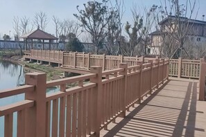 Eine hölzerne Brücke mit Geländern, die zu einem Gebäude mit einem überdachten Bereich führt.