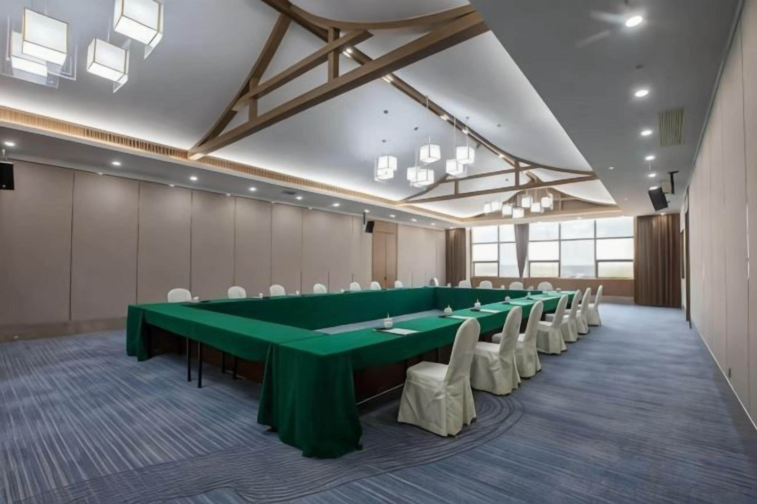 Une salle de conférence avec une longue table, des chaises et un sol recouvert de moquette.